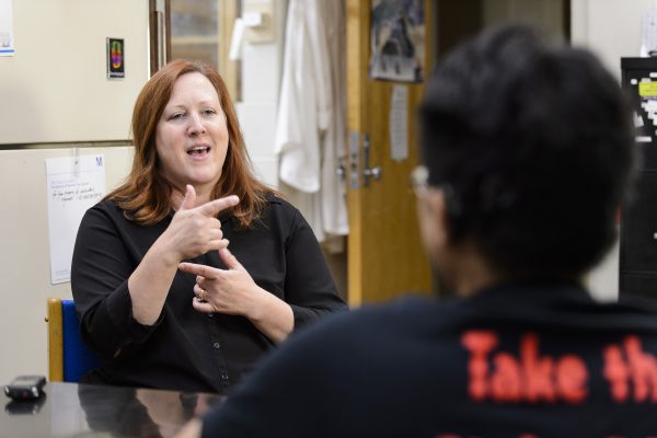 A sign language interpreter communicates with a student.