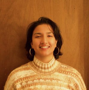 Jasnoor smiling against a brown background.